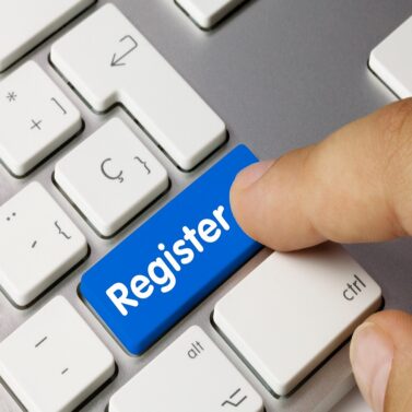 Keyboard with a button that says "register." Finger pushing button.